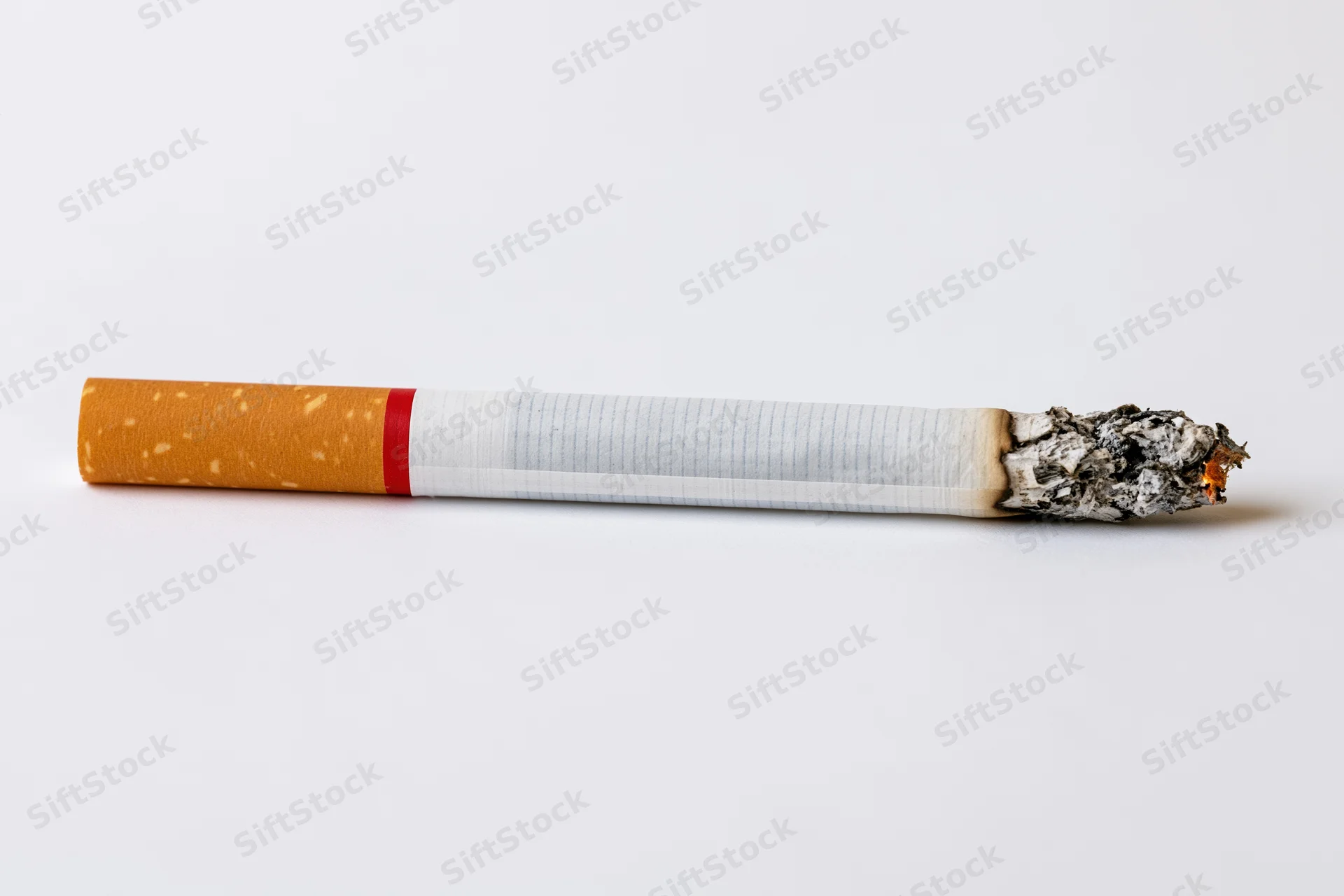 Lit cigarette with glowing ash tip on white background