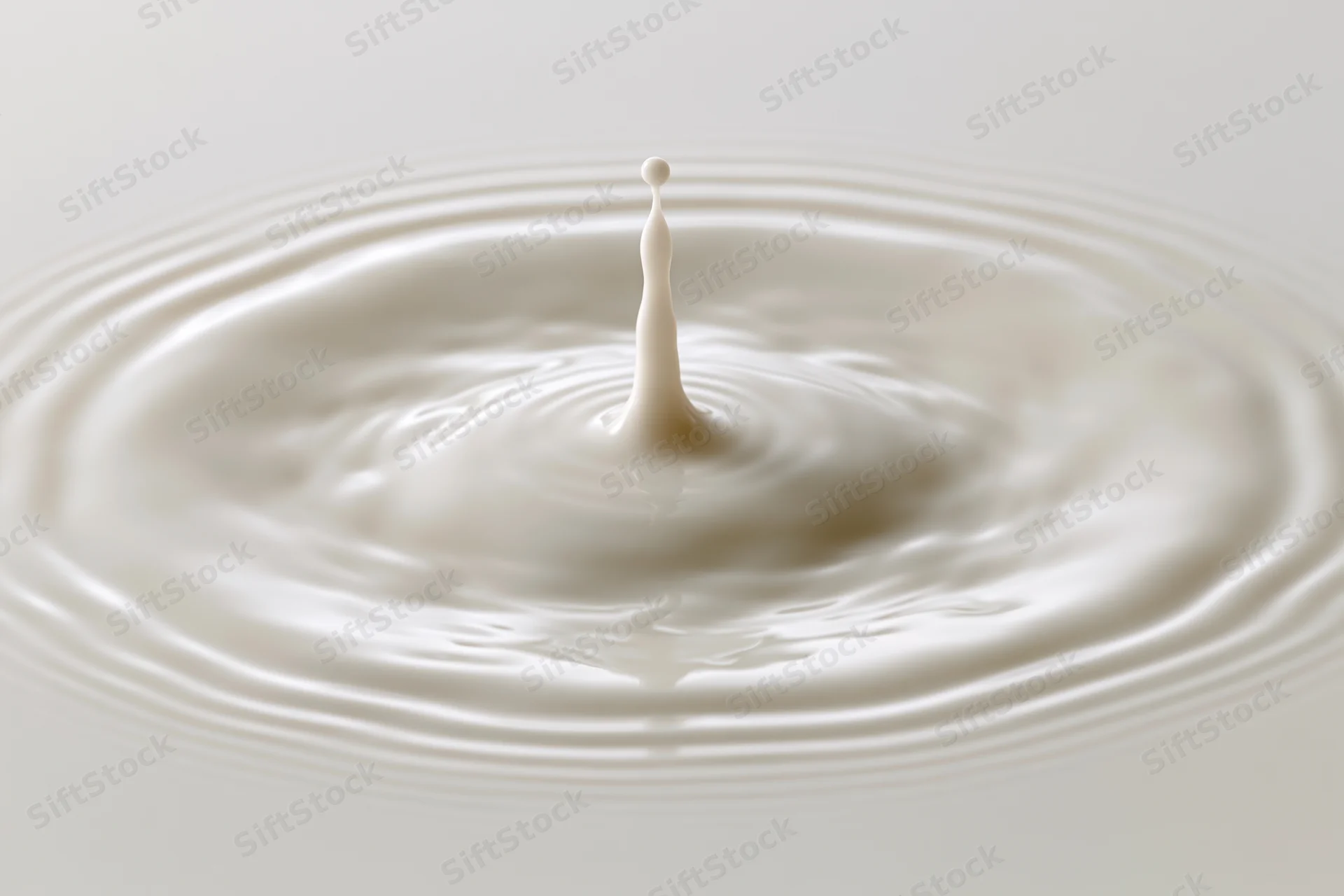 Milk drop frozen mid-splash creating ripples on a smooth surface