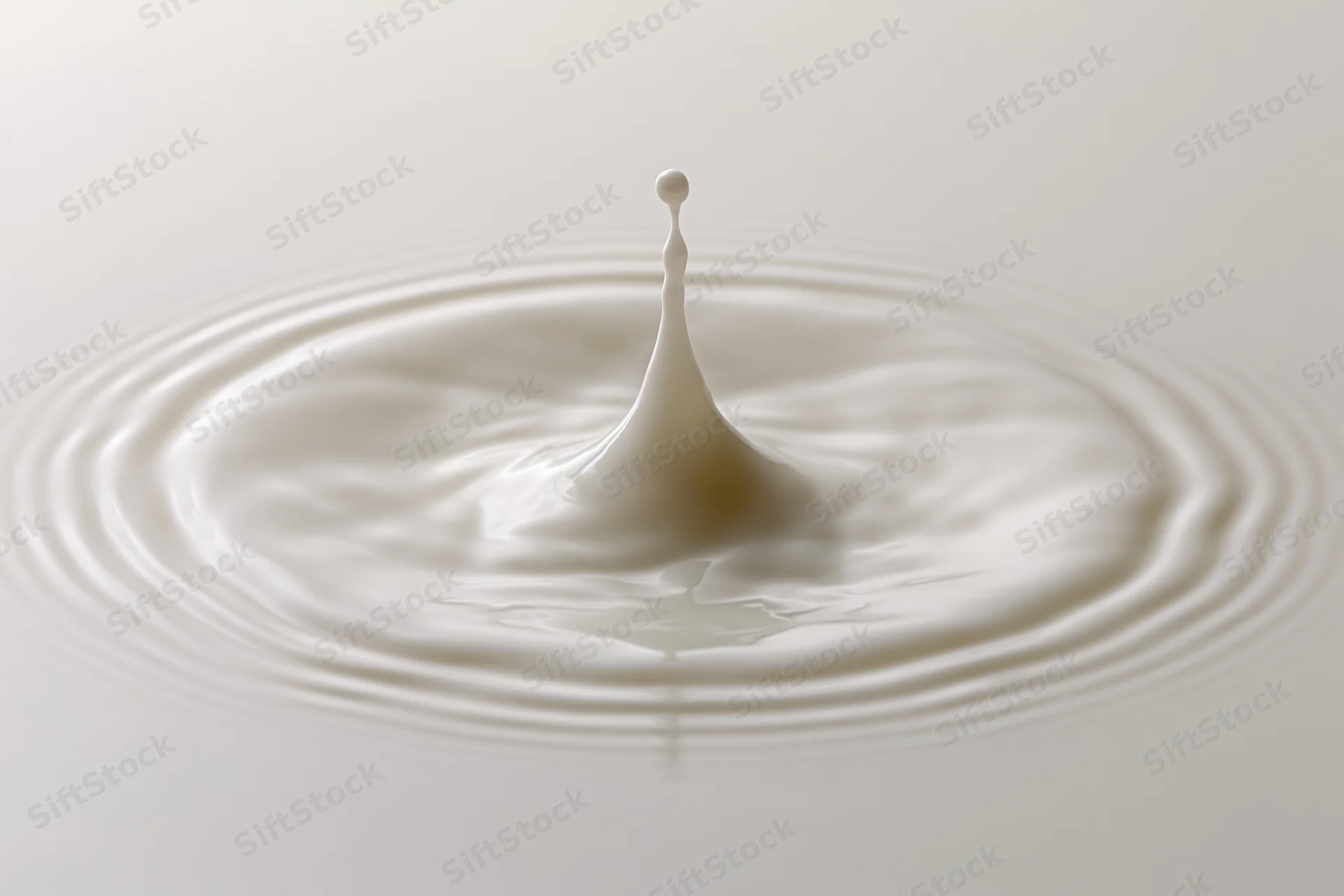 Milk drop frozen mid-splash creating crown and ripples on smooth surface