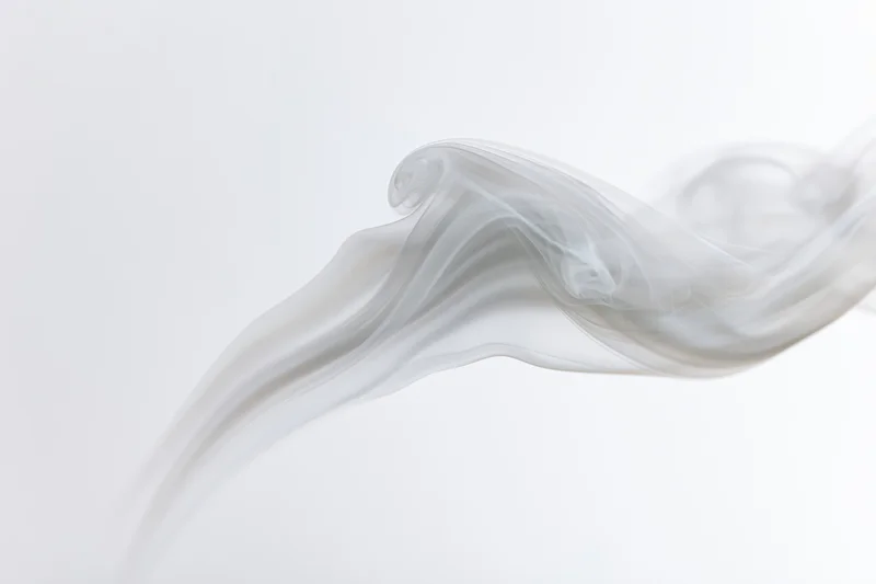 A thin wisp of white smoke curling upward against a plain white background