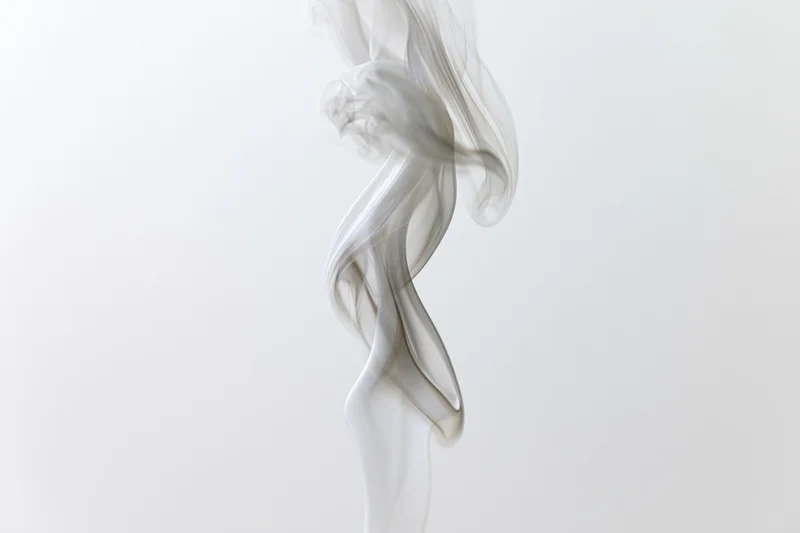 Thin wisp of white smoke curling upward against a plain white background