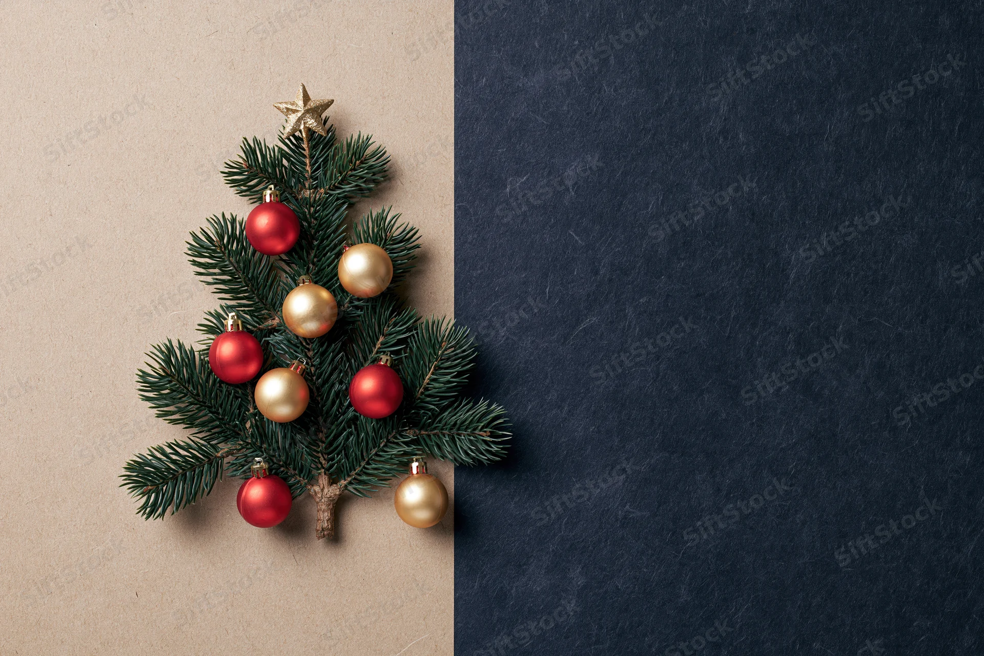 Small christmas tree made from pine branches with red and gold ornaments on textured paper background