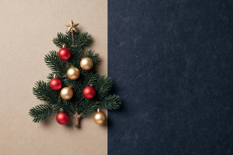 Small christmas tree made from pine branches with red and gold ornaments on textured paper background