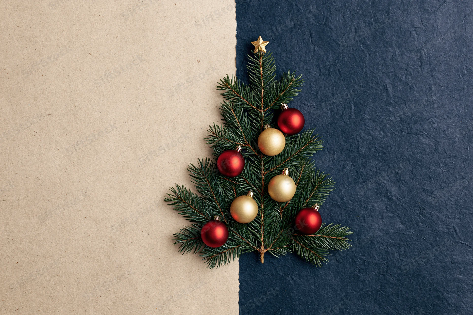 Pine branches arranged as a christmas tree with red and gold ornaments on a split beige and blue textured background