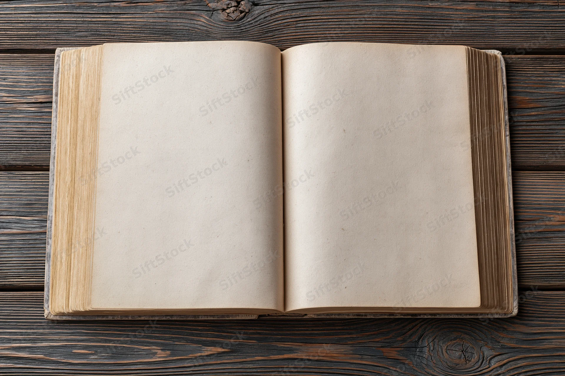 Open vintage hardcover book with blank aged pages on dark wooden table