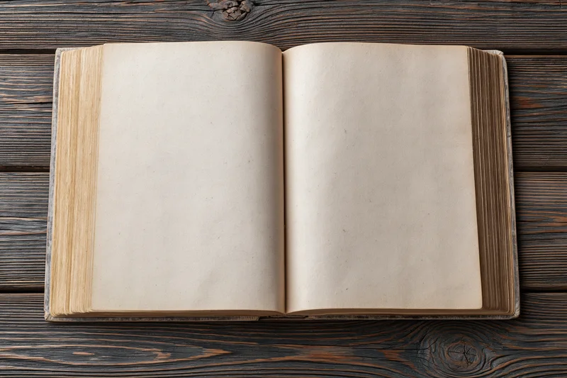 Open vintage hardcover book with blank aged pages on dark wooden table