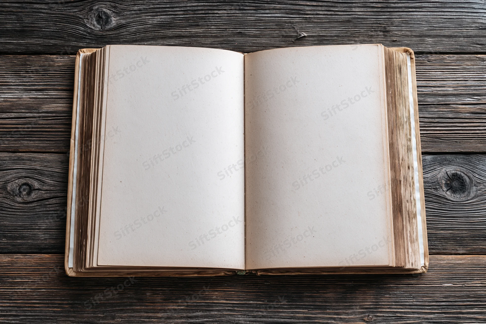 Open hardcover book with blank aged pages lying flat on dark wooden surface