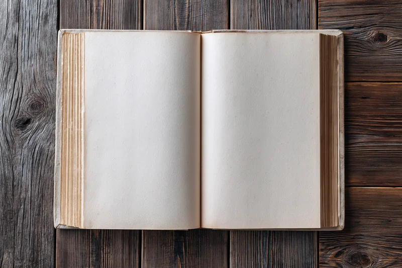 Open hardcover book with blank aged pages lying flat on wooden surface