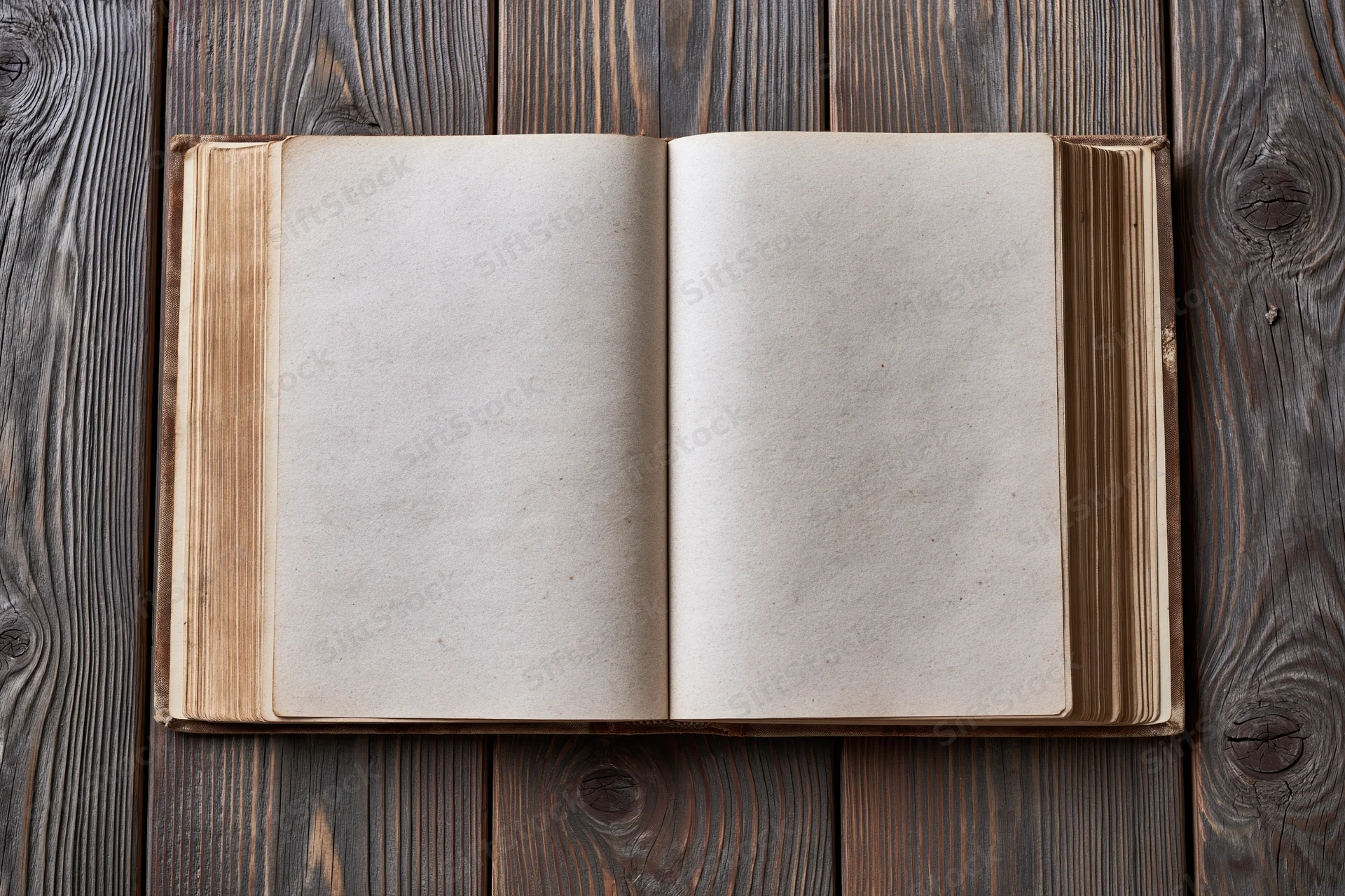 Open old hardcover book with blank aged pages on wooden surface