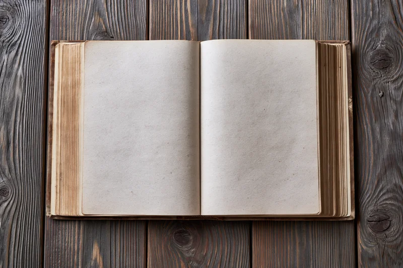 Open old hardcover book with blank aged pages on wooden surface
