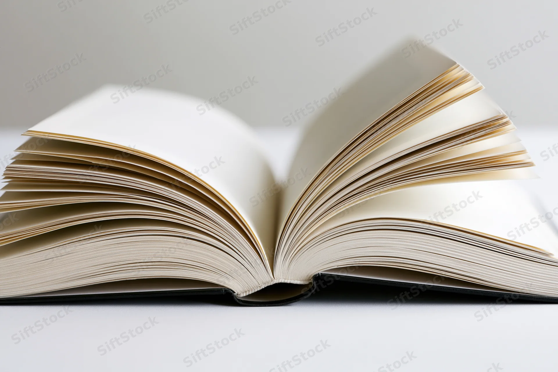 Open hardcover book with pages fanned outward symmetrically on a white surface