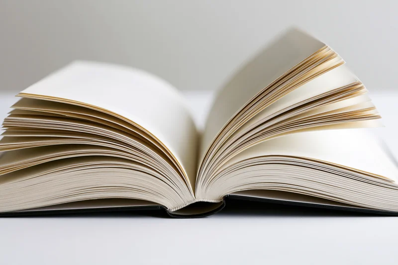 Open hardcover book with pages fanned outward symmetrically on a white surface