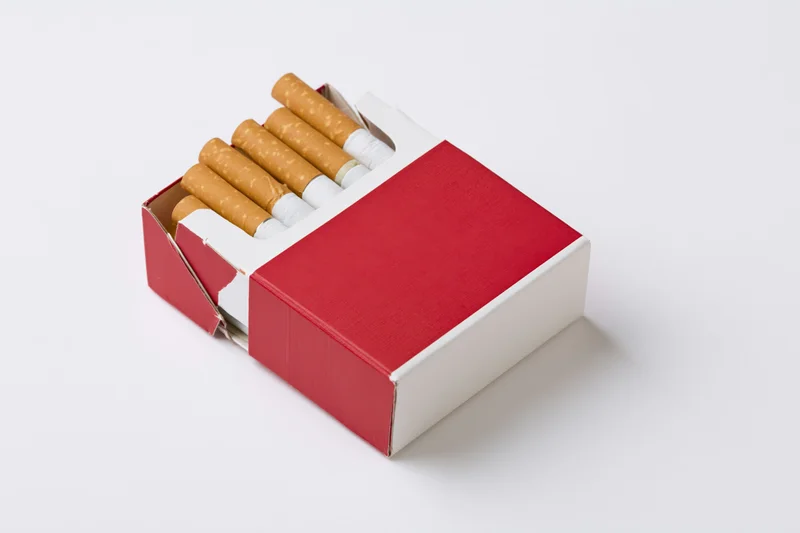 Open red and white cigarette pack with several cigarettes on white background