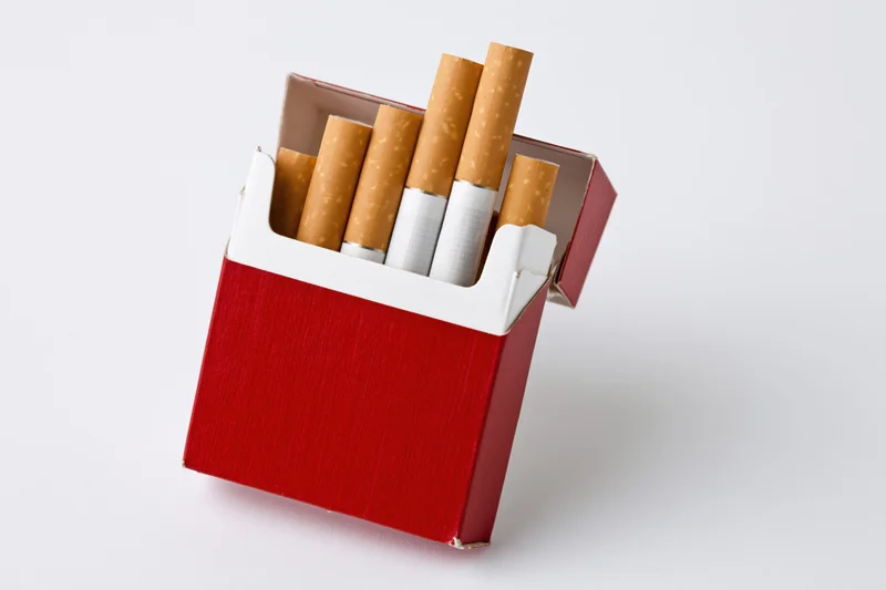 Open red and white cigarette pack with several cigarettes visible against white background
