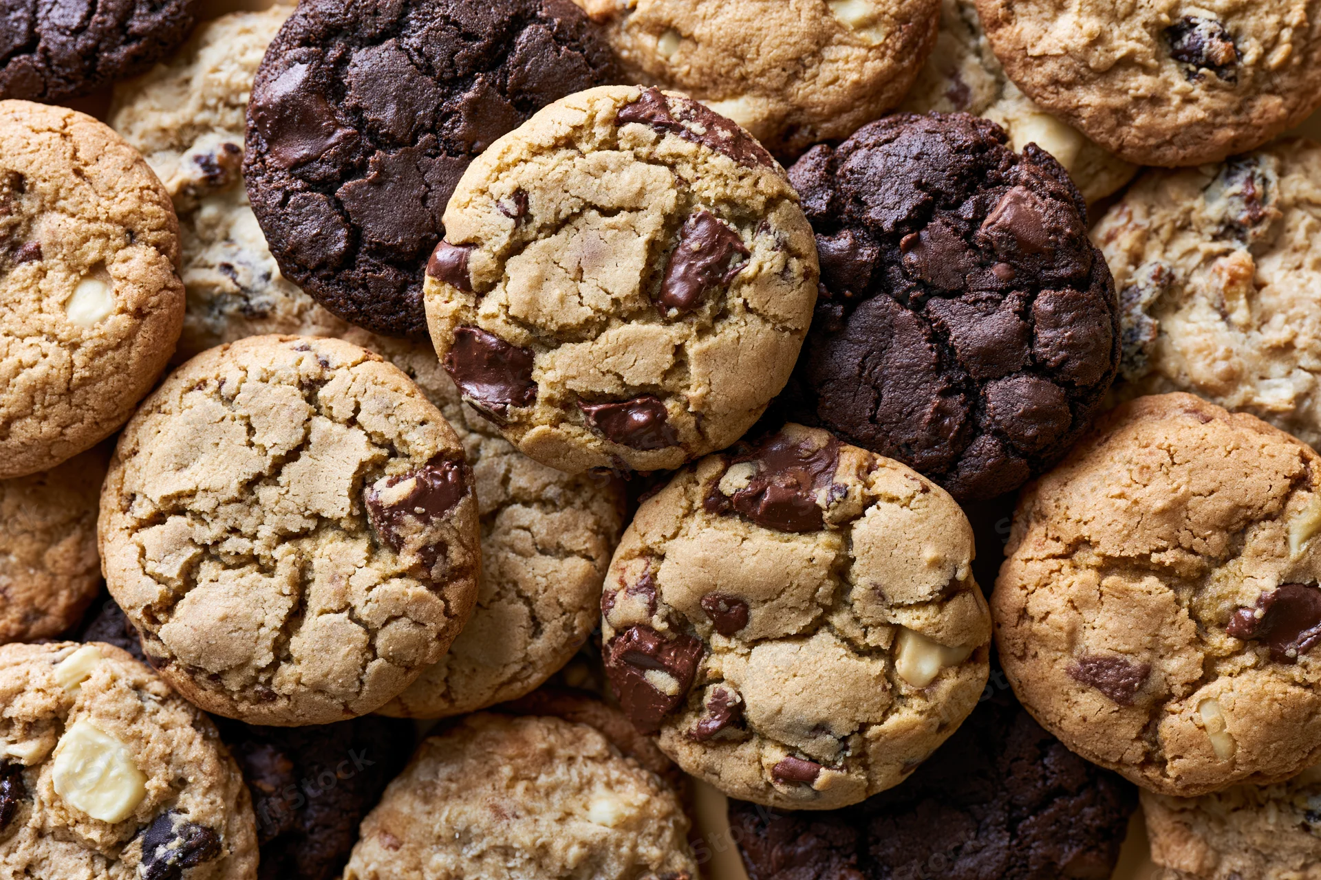 Assorted homemade cookies piled together filling the frame in close-up overhead view