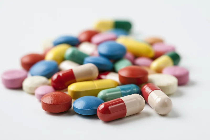 Assorted pharmaceutical pills and capsules scattered loosely on a white surface