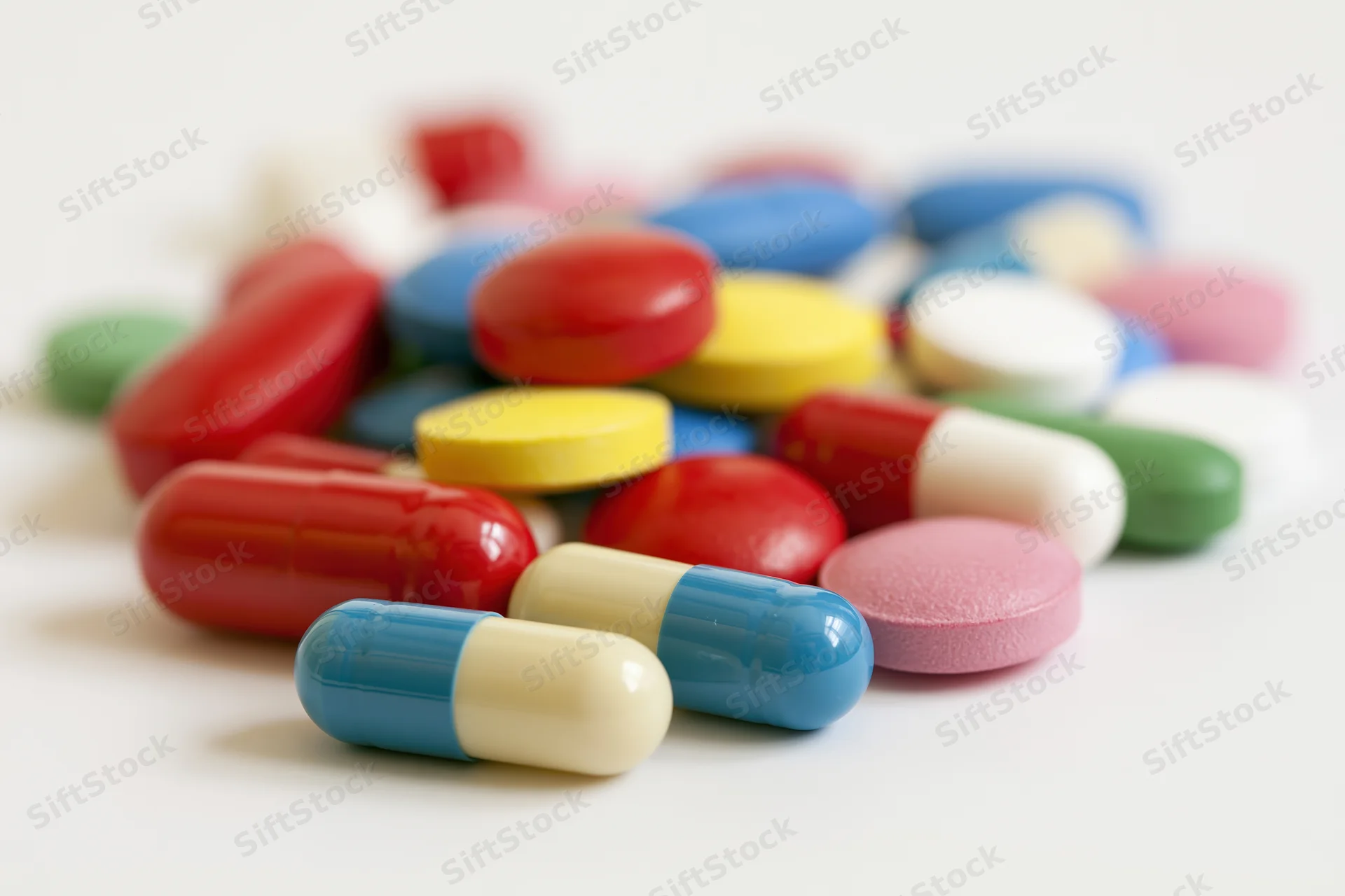 Assorted pharmaceutical pills and capsules scattered loosely on a white surface