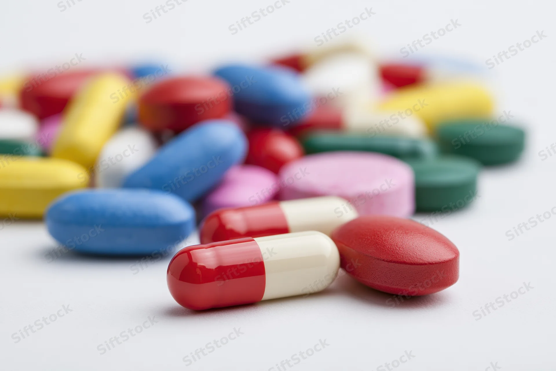 Assorted pharmaceutical pills and capsules scattered on a white surface