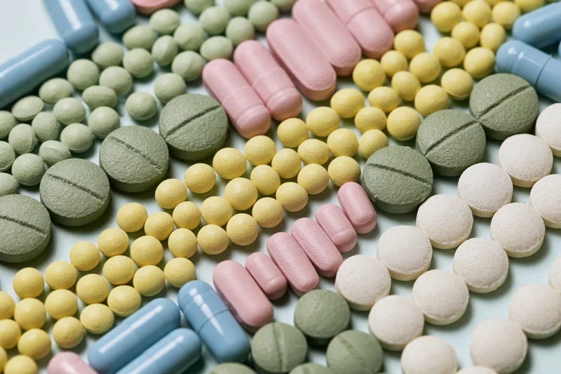 Assorted medication tablets and capsules scattered on a light surface