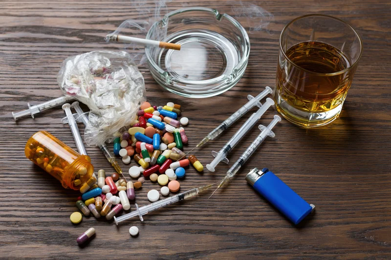 Assorted substance use items scattered on a dark wooden table