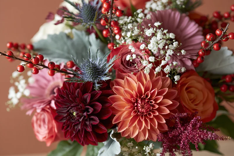 Autumn floral bouquet with dahlias, roses, berries and thistle arranged in a centerpiece display