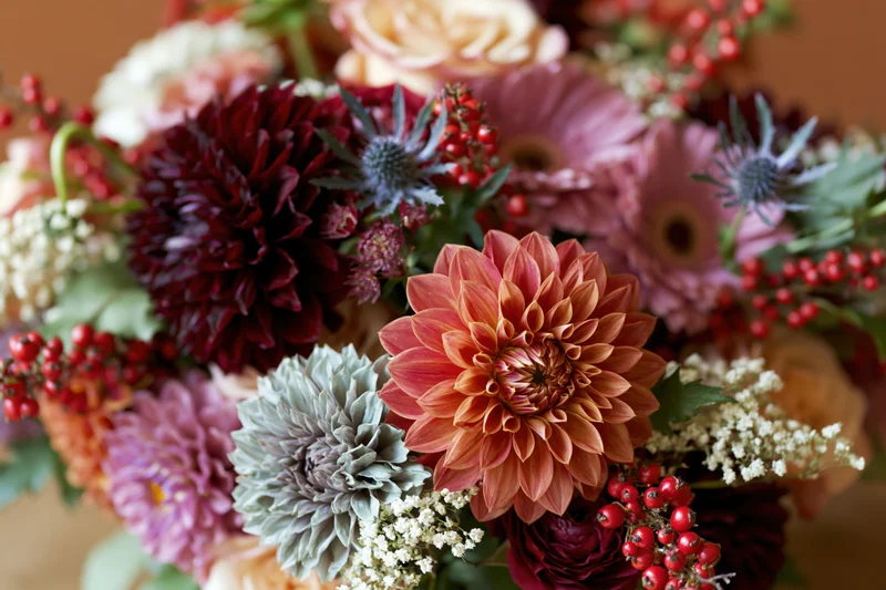 Autumn floral bouquet with dahlias, roses, thistles and berries arranged as centerpiece