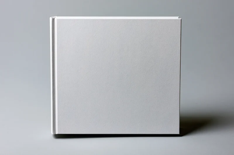 Blank white hardcover book standing upright on a gray surface