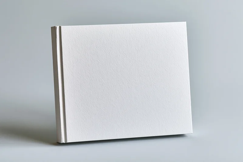 Blank hardcover book standing upright on a gray surface with plain white cover for design mockup