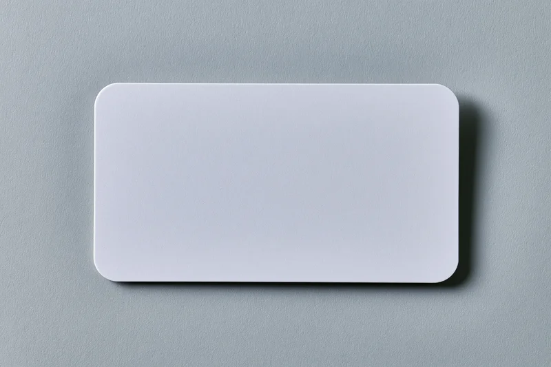 Blank white business card lying flat on light grey textured paper surface