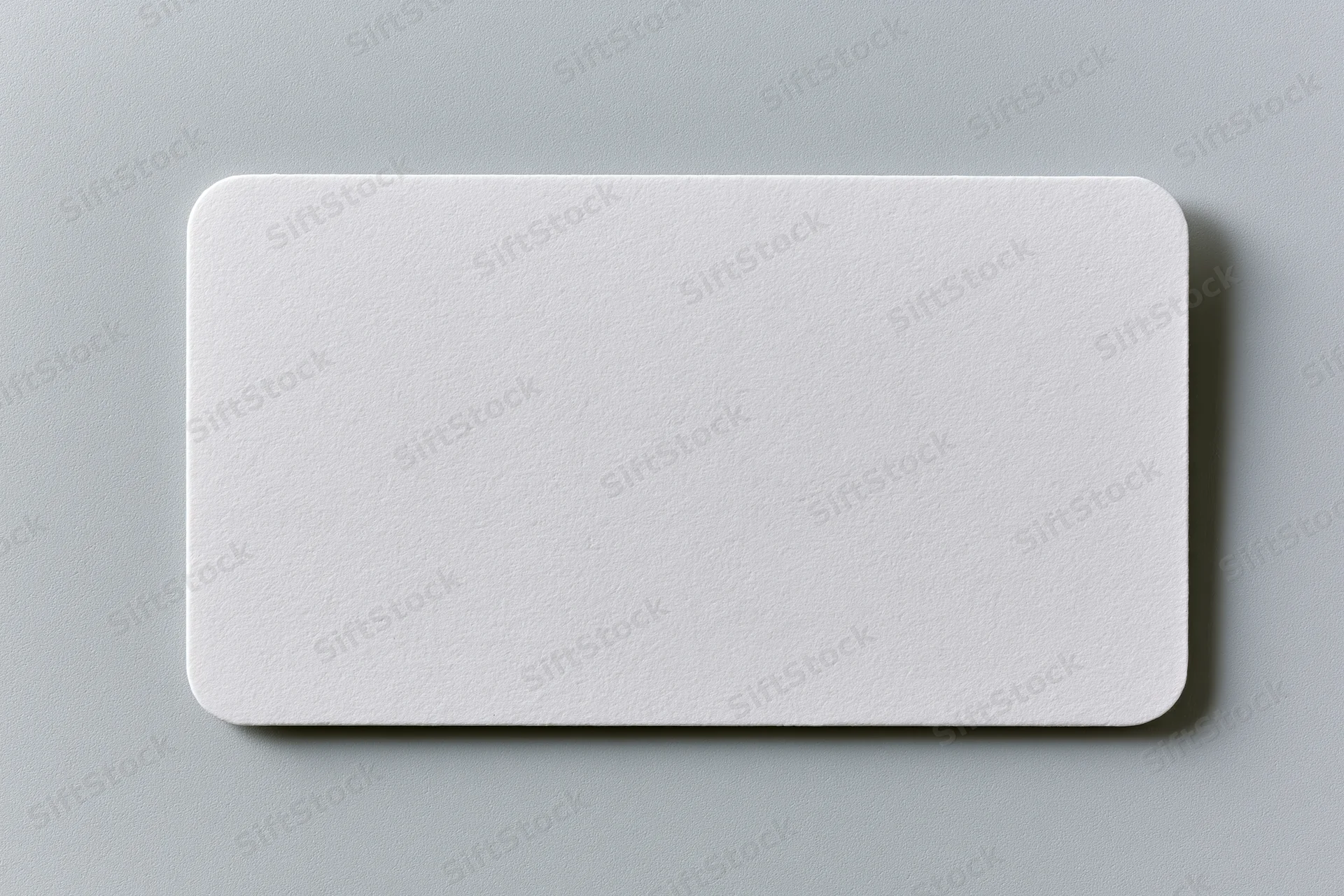 Blank white business card lying flat on a light gray textured paper surface