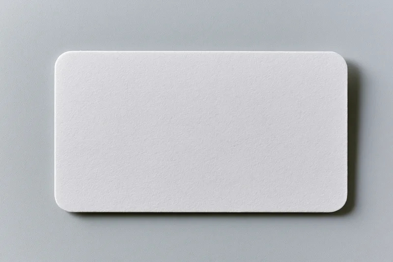 Blank white business card lying flat on a light gray textured paper surface