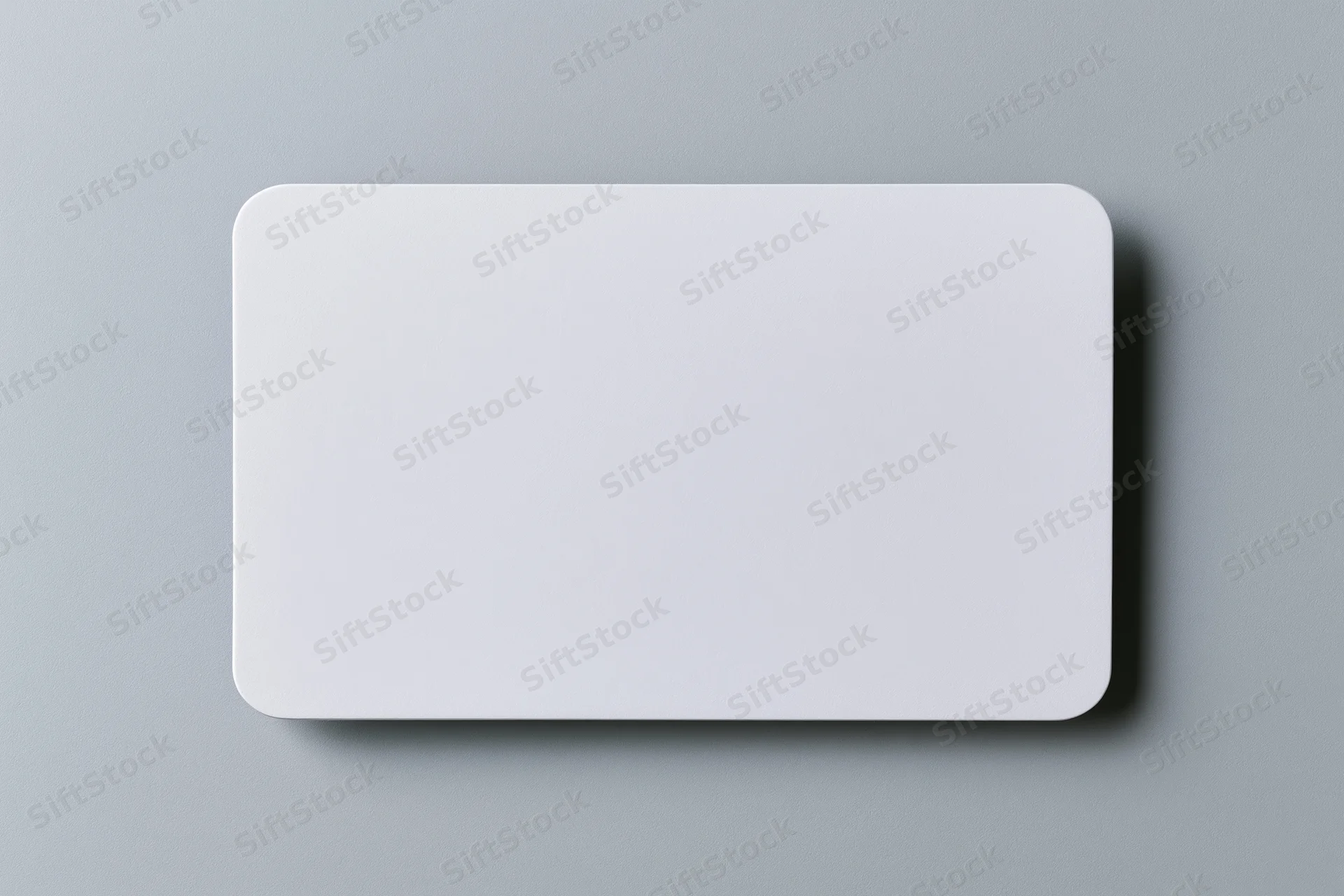 Blank white business card lying flat on light grey paper surface