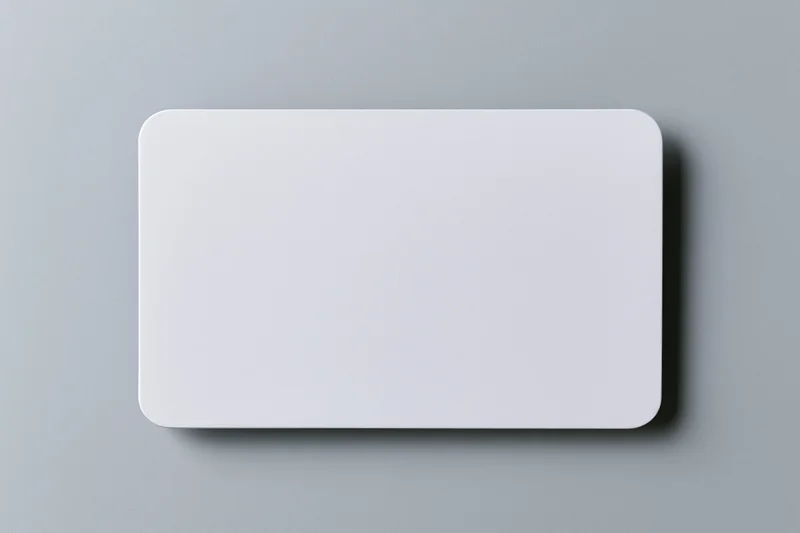 Blank white business card lying flat on light grey paper surface