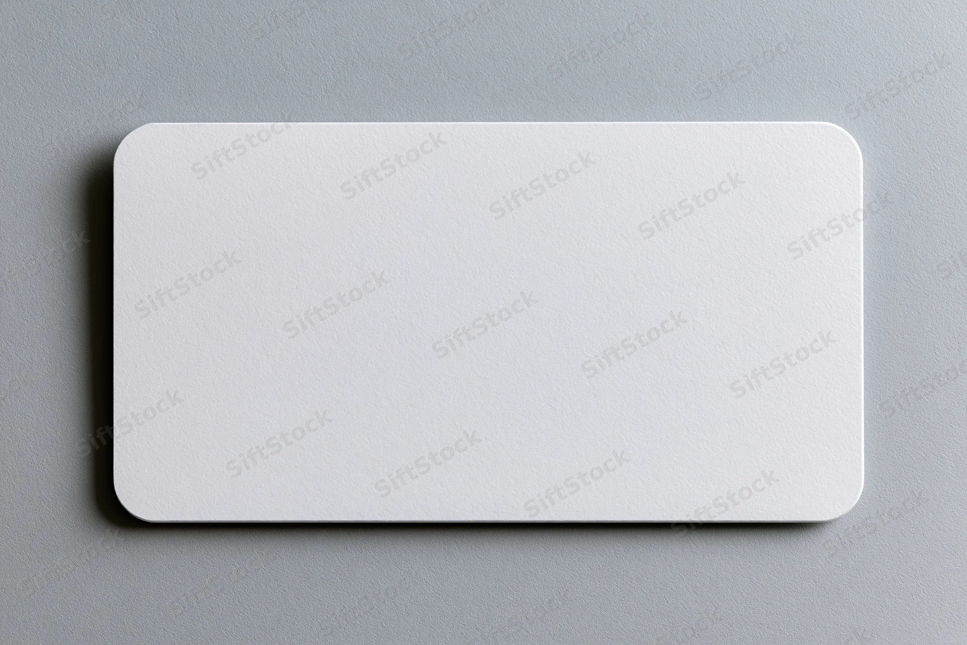 Blank white business card lying flat on a grey textured surface