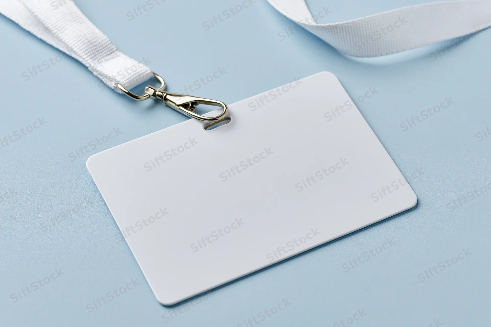 Blank white plastic badge card attached to white fabric lanyard on light blue surface