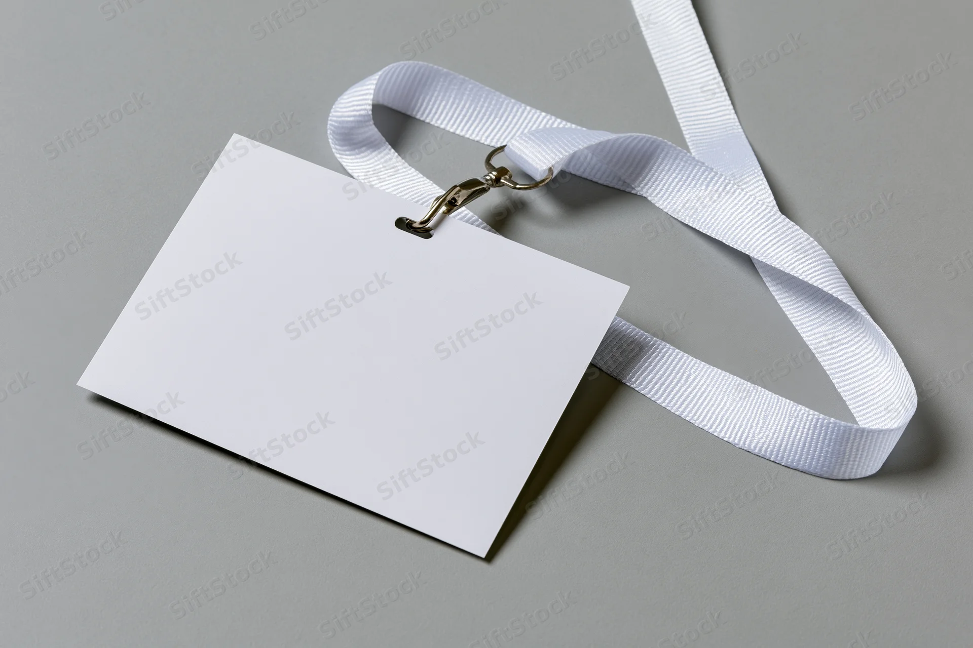 Blank white ID badge attached to white woven lanyard on gray surface