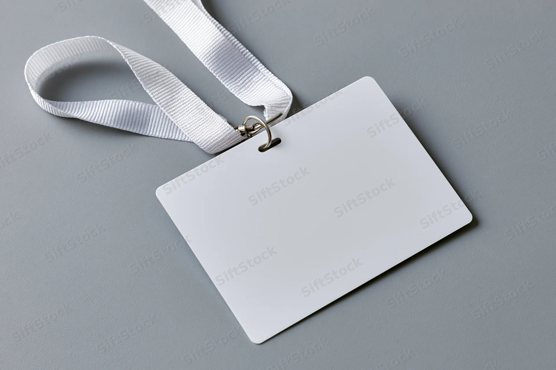 Blank white id badge on white lanyard lying on gray surface