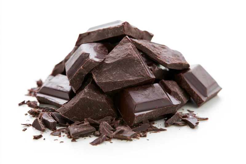 Broken dark chocolate chunks piled loosely on a clean white surface