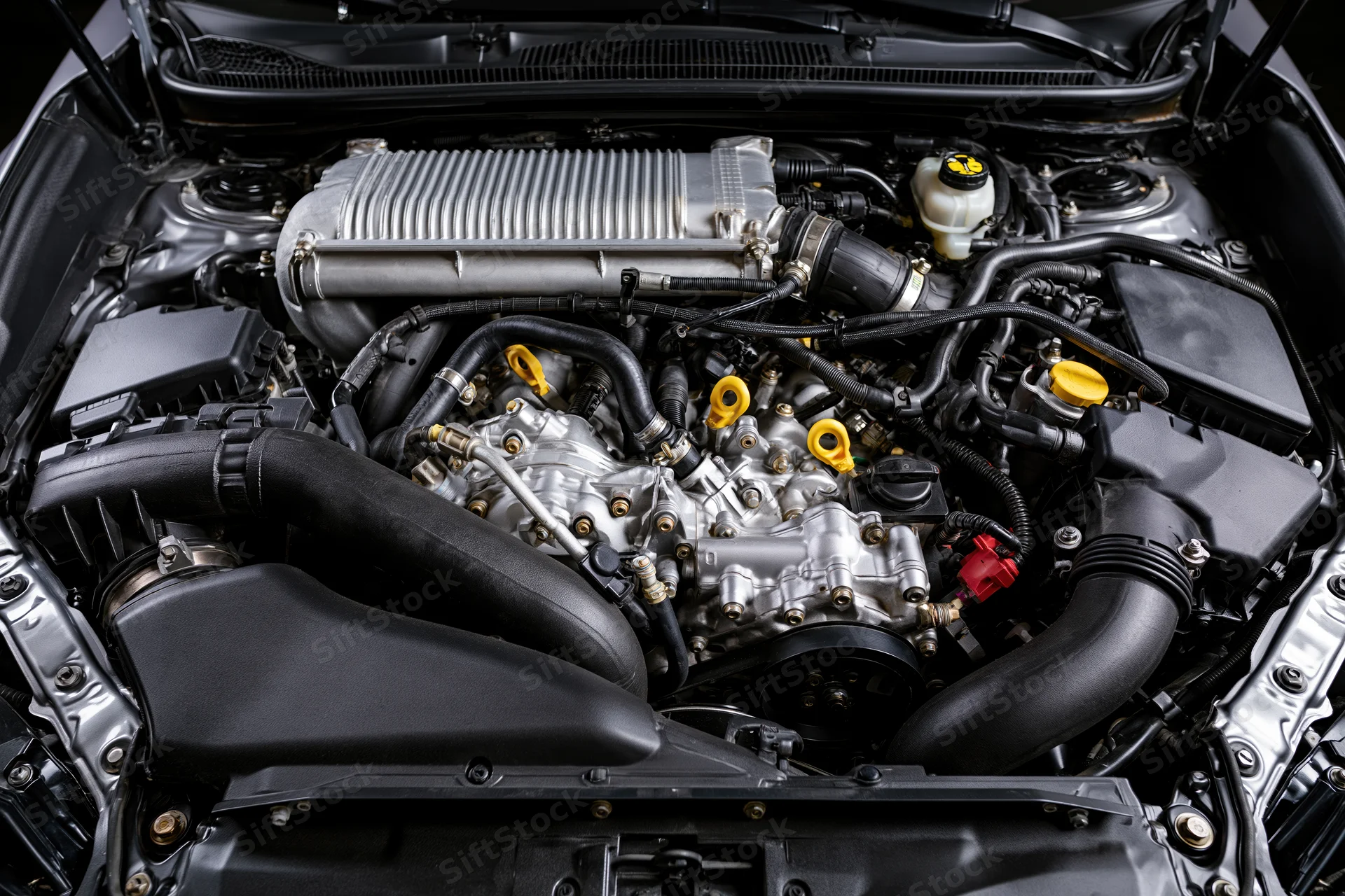 Car engine bay with open hood showing intercooler and mechanical components