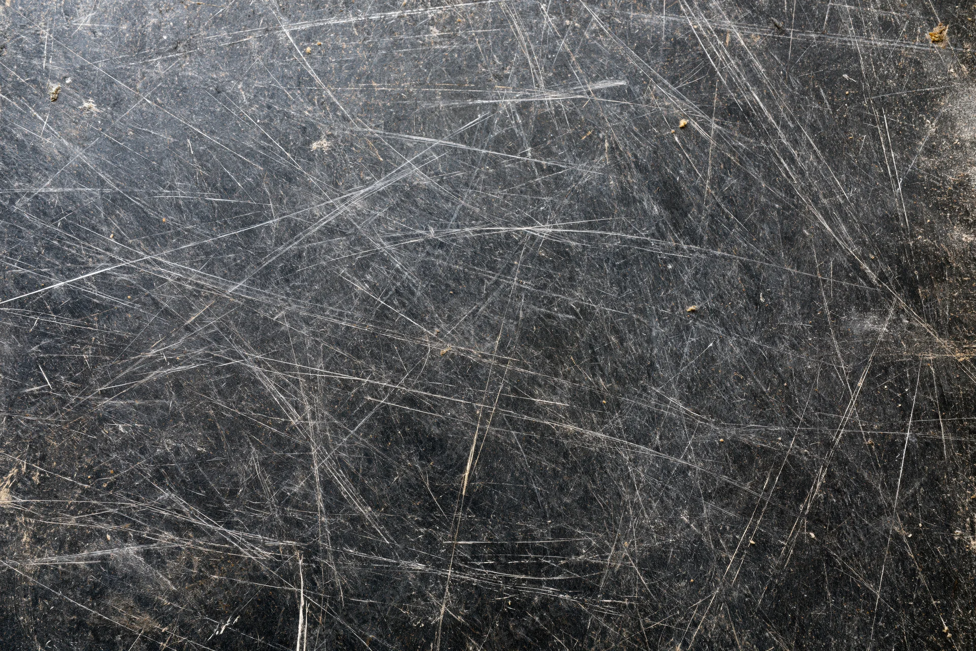 Close-up of a heavily scratched dark metal surface showing wear and tear