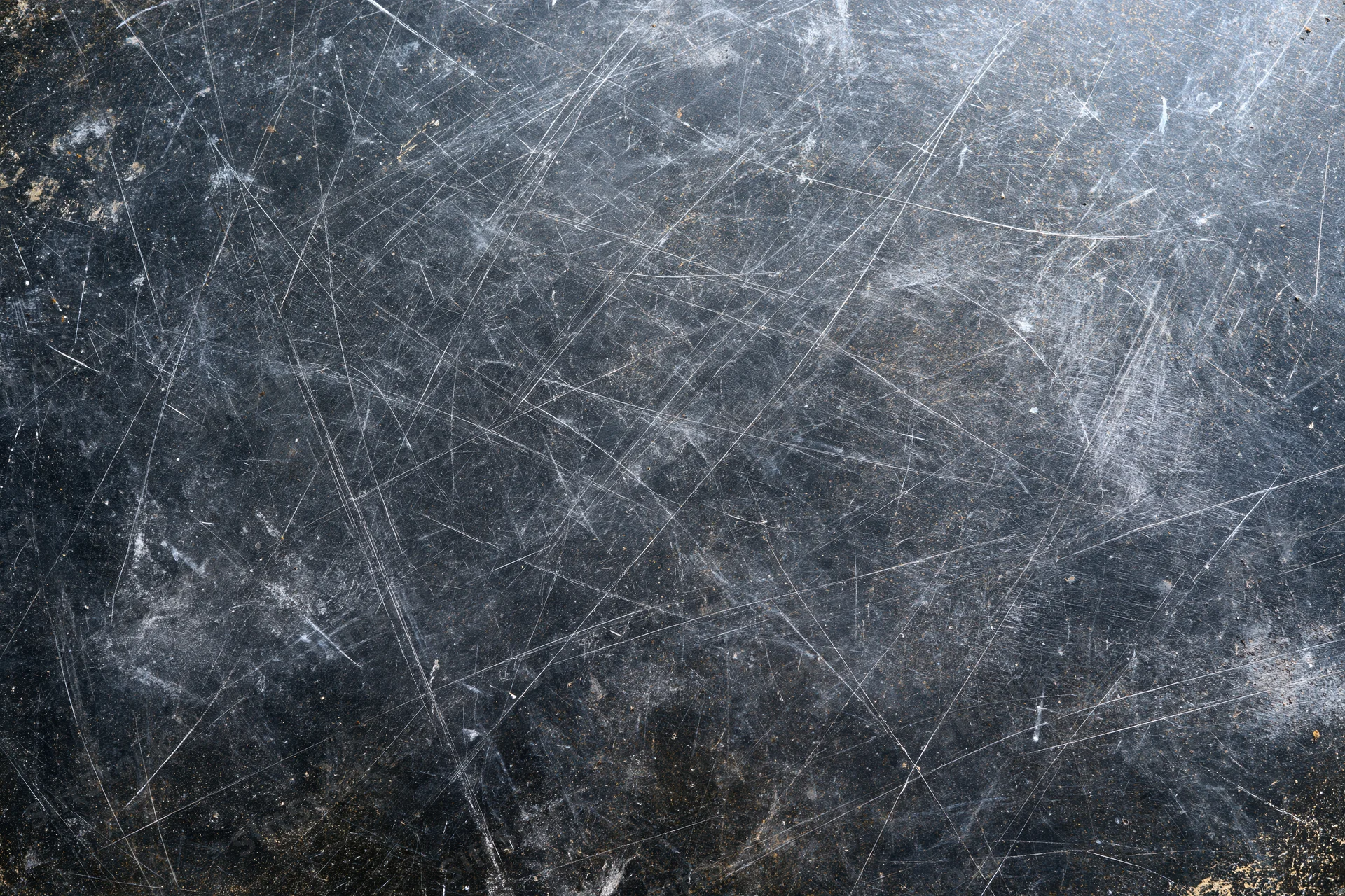 Close-up of heavily scratched dark metal surface with visible wear and texture