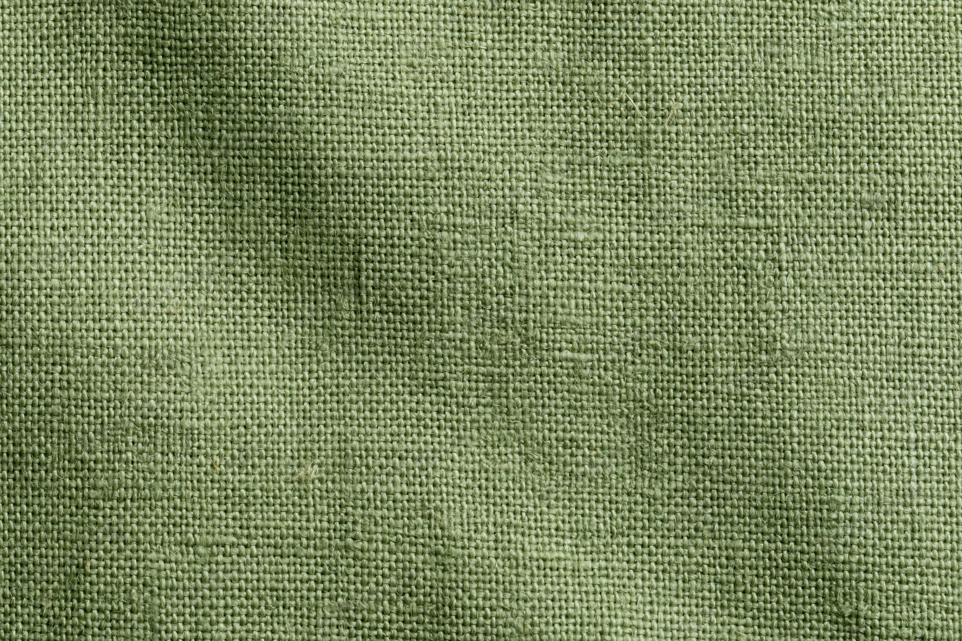 Close-up of sage green linen fabric with visible weave pattern filling the frame