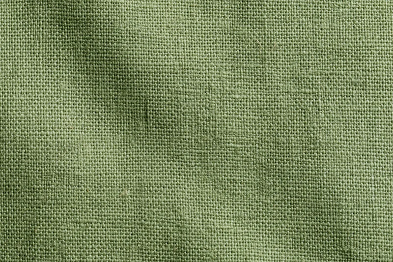 Close-up of sage green linen fabric with visible weave pattern filling the frame