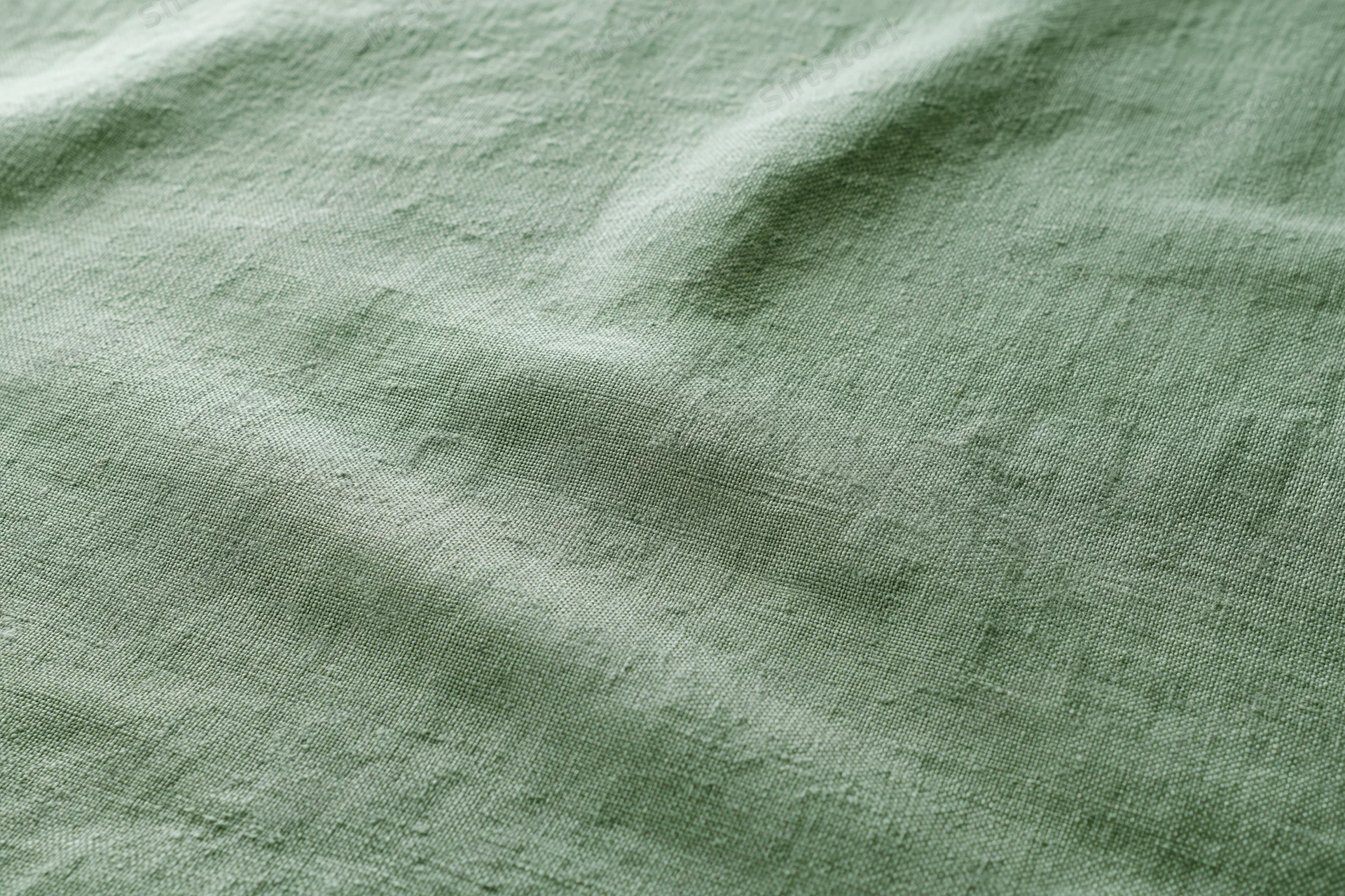 Close-up of sage green linen fabric with natural weave texture filling the frame