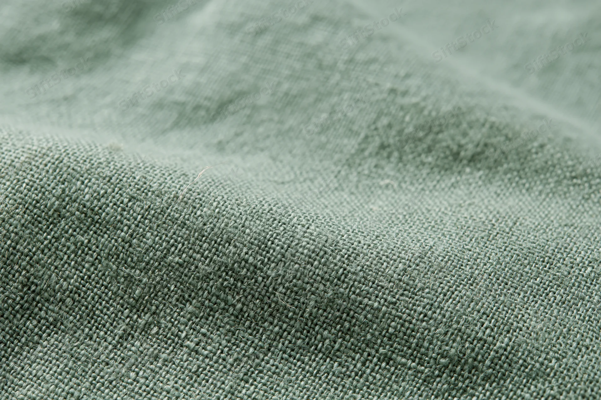 Close-up of sage green linen fabric with visible weave and texture filling the frame