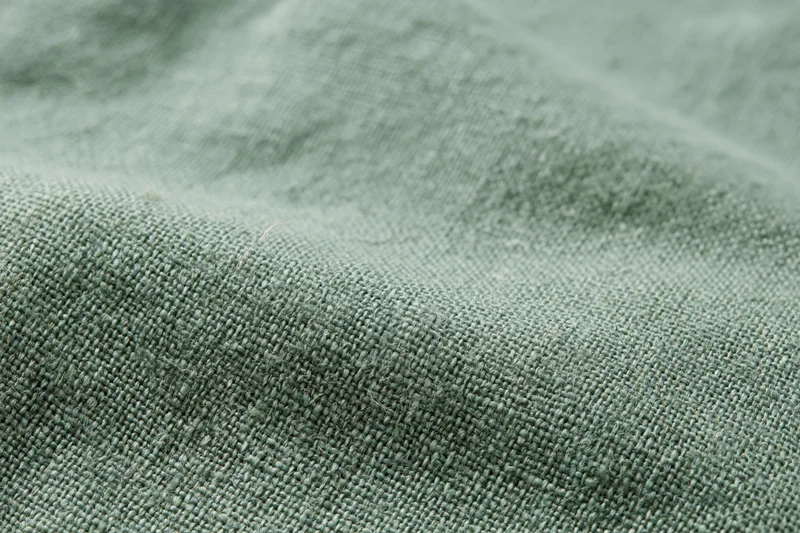 Close-up of sage green linen fabric with visible weave and texture filling the frame