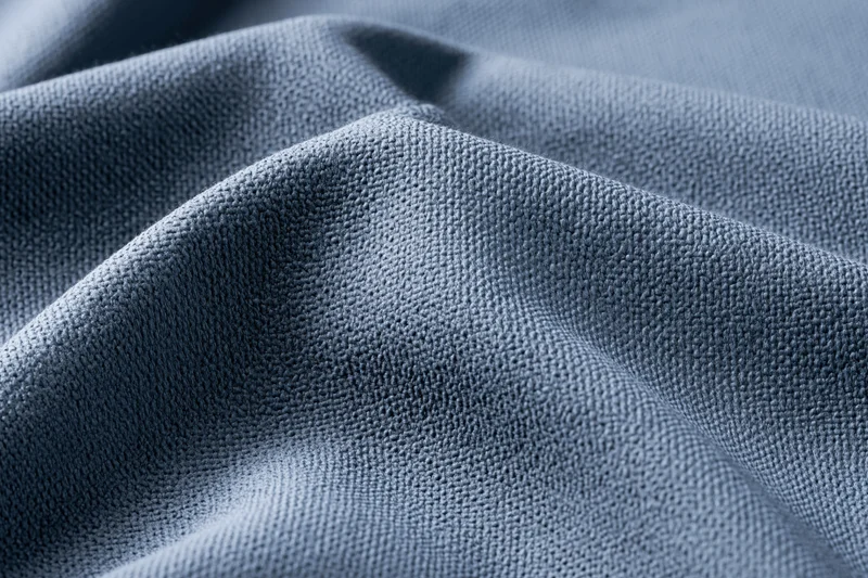 Close-up of steel-blue textured fabric with visible weave and folds filling the frame