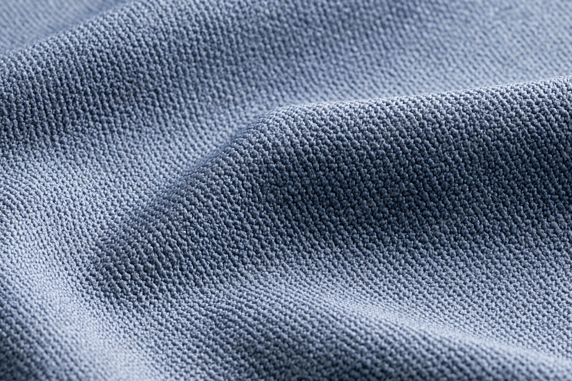Close-up of steel-blue textured fabric with visible weave and folds filling the frame