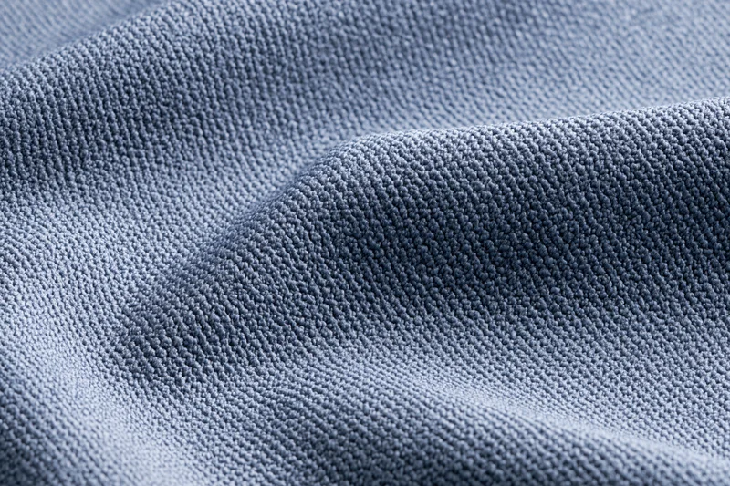 Close-up of steel-blue textured fabric with visible weave and folds filling the frame
