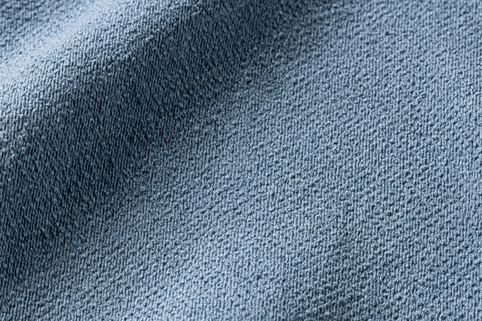 Close-up of steel-blue textured fabric with visible weave and folds filling the frame